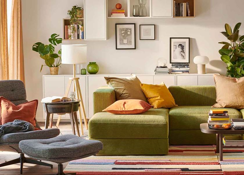 Lounge with green corner sofa, grey chair and orange cushios