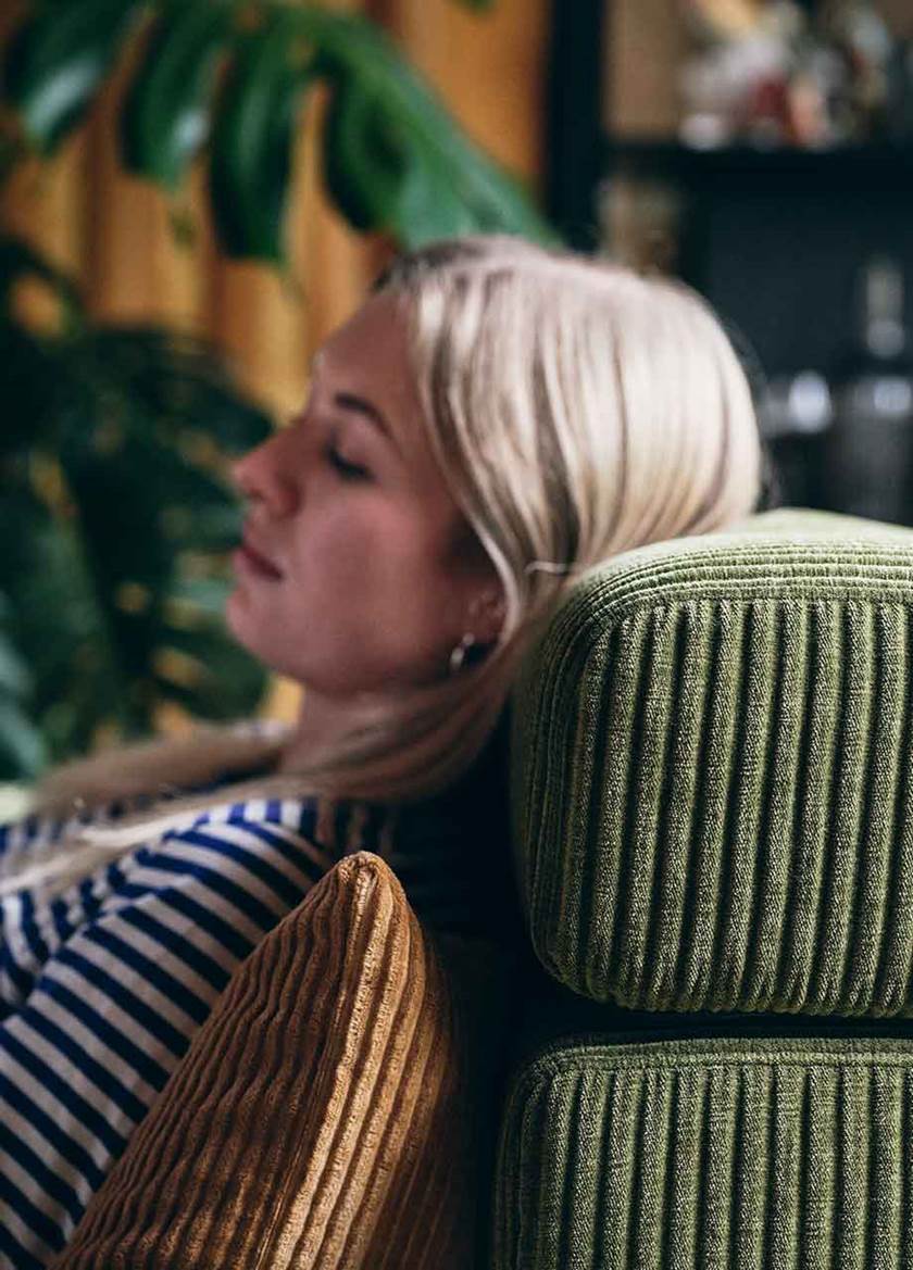 Woman sat resting head on a green sofa